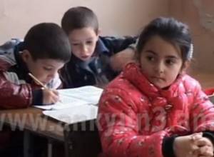 Children do lessons huddled against cold