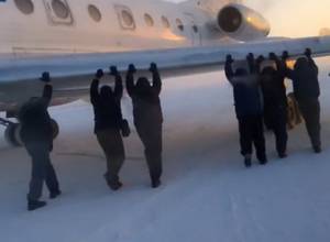 Passengers get out and push frozen plane