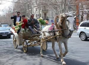 Women and girsl receive flowers from horse-drawn carriage