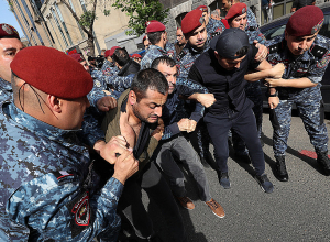 Полицейские задерживают демонстрантов, шагающих по тротуару